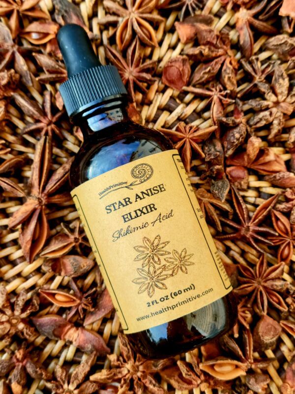 A bottle of star anise elixir sitting on top of dried flowers.