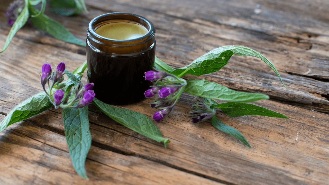A jar of honey and purple flowers on a table.