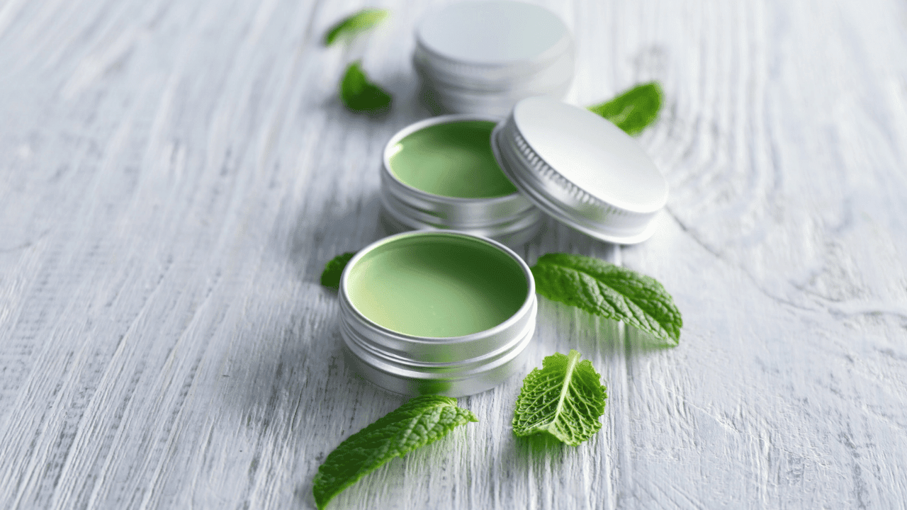 A close up of three containers with green lip balm