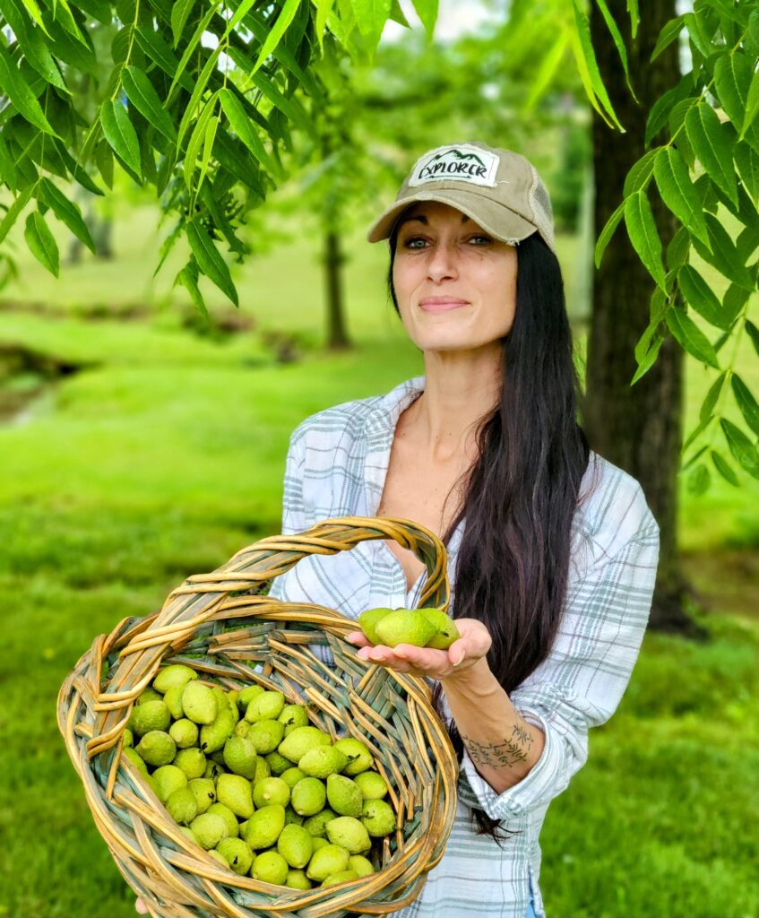 A woman holding an apple and a basket of apples.