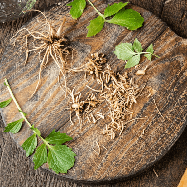 A wooden cutting board with some leaves and grass on it