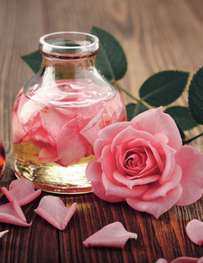 A glass bottle with pink rose petals in it.